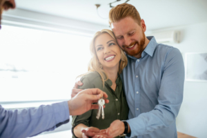 Happy couple accepting their new house keys from their real estate agent